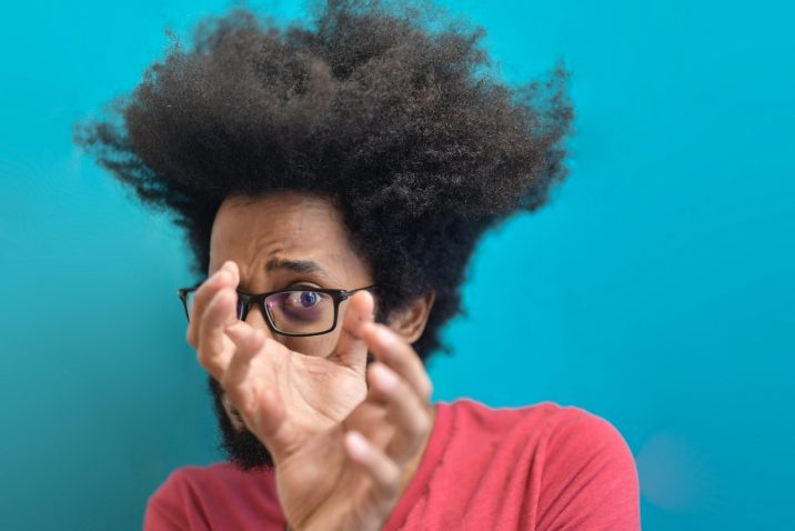 Afraid man looking through hands