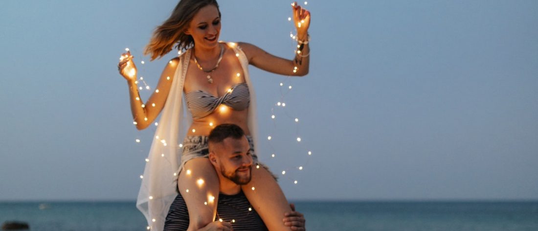 Woman sitting on the shoulder of her partner on a beach
