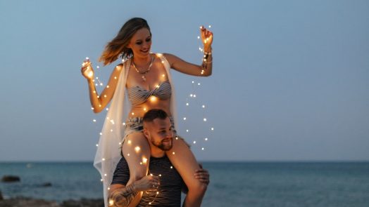 Woman sitting on the shoulder of her partner on a beach
