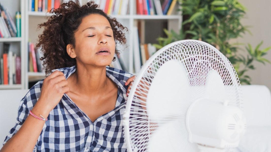 Woman having a hot flash in front of a fan