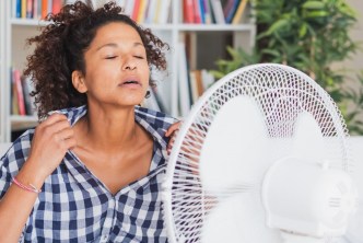 Woman having a hot flash in front of a fan